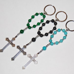 May include: Three beaded keychains with silver cross charms. The keychains feature green, black, and turquoise beads.