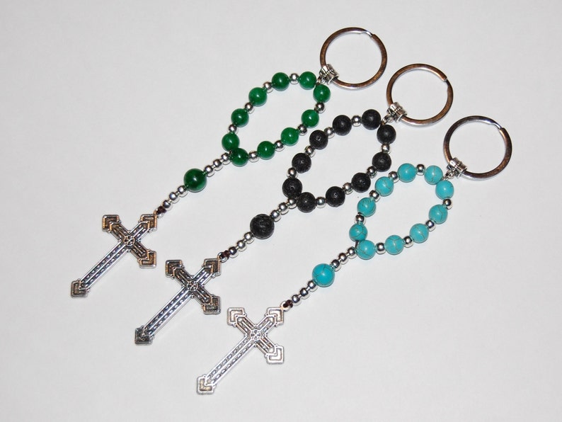 May include: Three beaded keychains with silver cross charms. The keychains feature green, black, and turquoise beads.