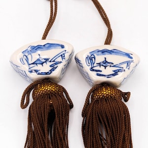 Peut inclure: Deux glands de porcellane bleu et blanc avec des glands bruns. La porcelaine est décorée d'une scène de paysage bleu et blanc.