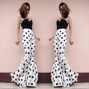 Puede incluir: Dos mujeres con crop tops negros y pantalones blancos con lunares negros. Los pantalones son acampanados y tienen una pierna ancha.