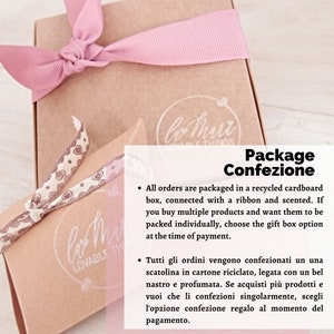 Pu&ograve; includere: Primo piano di una scatola di cartone marrone con un nastro rosa legato intorno. La scatola &egrave; etichettata con "lo mart lovable things" e "Package Confezione". Il testo sotto l'etichetta dice: "All orders are packaged in a recycled cardboard box, connected with a ribbon and scented. If you buy multiple products and want them to be packed individually, choose the gift box option at the time of payment." Il testo sotto quello dice: "Tutti gli ordini vengono confezionati un una scatolina in cartone riciclato, legata con un bel nastro e profumata. Se acquisti pi&ugrave; prodotti e vuoi che li confezioni singolarmente, scegli l'opzione confezione regalo al momento del pagamento."