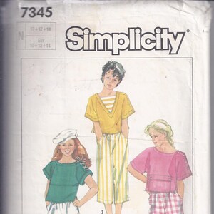 Puede incluir: Patrón de costura Simplicity con tres conjuntos diferentes. Los conjuntos incluyen tops y pantalones en varios colores y patrones. El número de patrón es 7345, y las tallas son 10+12+14.