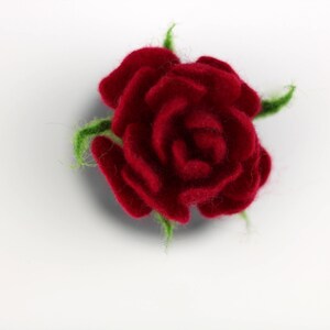 Puede incluir: Una rosa roja de fieltro con hojas verdes de fieltro. La rosa es un art&iacute;culo artesanal.