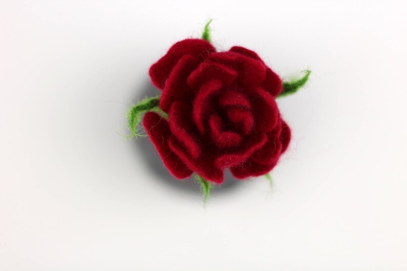 Puede incluir: Una rosa roja de fieltro con hojas verdes de fieltro. La rosa es un art&iacute;culo artesanal.