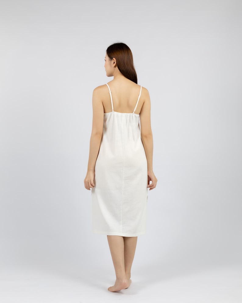 May include: A white sleeveless midi dress with a scoop neck and a simple design. The dress is made of a soft, flowing fabric.