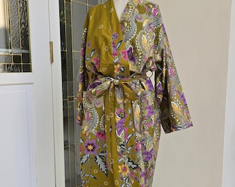 Könnte beinhalten: Eine grüne und violette, floral gemusterte Robe mit einem Bindegürtel. Die Robe befindet sich auf einem Mannequin.