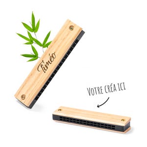 Puede incluir: Una armónica de madera con una placa de lengüetas de metal negro. La armónica está grabada con el nombre "Timéo" y las palabras "Votre Créa Ici".