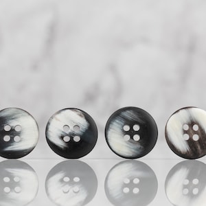 May include: Four black and white horn buttons with four holes each.