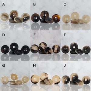 May include: A collection of various-sized buttons in shades of brown, tan, and cream. Each button has four holes and a slightly domed surface. The buttons are arranged in groups, with larger and smaller sizes.