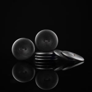 May include: A stack of black buttons with a round shape and a single hole in the centre. The buttons are arranged in a pyramid shape with the largest button at the top.