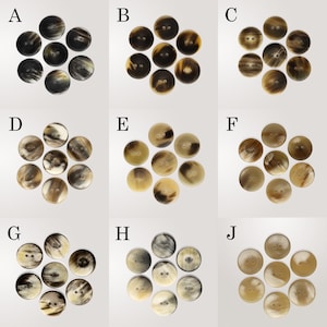 May include: A selection of ten round buttons in shades of brown, tan, and cream. Each button has two or four holes for sewing. The buttons are arranged in a circular pattern, displaying their natural colour variations and textures.