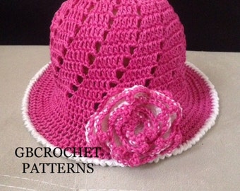May include: A pink crocheted sun hat with a white crocheted flower on the side. The hat has a wide brim and a white trim. The text "GBCROCHET PATTERNS" is visible in the bottom left corner of the image.