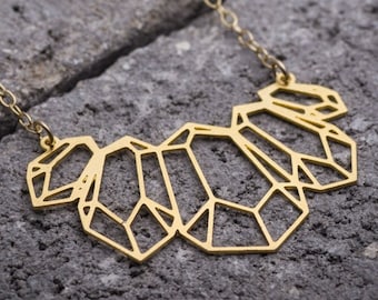 ゴールドの幾何学模様のネックレス。現代女性のための大胆な