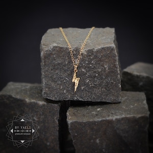 Colar minimalista com pingente de raio dourado em formato de raio.