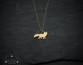 May include: A gold-toned necklace featuring a small, flat fox-shaped pendant suspended from a delicate chain. The pendant is a solid silhouette of a standing fox. In the bottom left corner, a logo reads BY YAELI UNIQUE JEWELRY DESIGN.