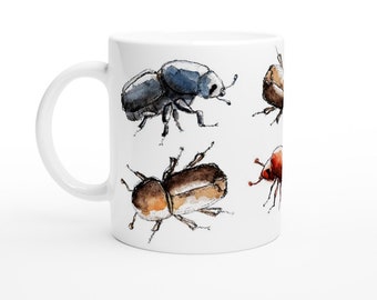Puede incluir: Taza de cerámica blanca con un diseño de seis escarabajos diferentes en estilo acuarela. Los escarabajos son de varios tonos de marrón, azul y rojo.