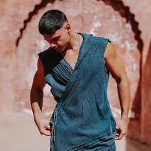 May include: A sleeveless, wrap-style top and matching pants in a muted teal color. The top features a draped design with pleats and a tie closure. The outfit is made of a soft, flowing fabric, perfect for warm weather.
