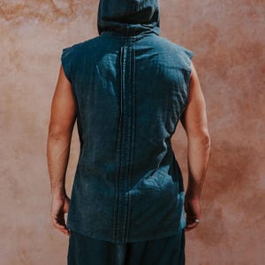 May include: A sleeveless hooded top and matching pants in a muted teal color. The top features a vertical seam detail down the back. The outfit is made of a soft, textured fabric, perfect for casual wear.