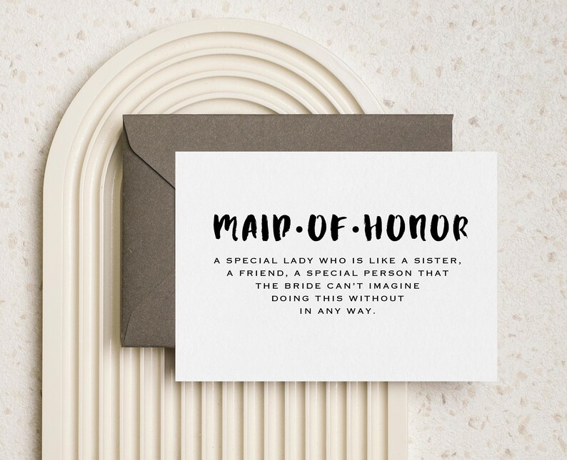 May include: A white card with black text that reads "Maid of Honor" and a description of what a maid of honor is. The card is sitting on a white and brown background.