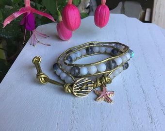 May include: A triple wrap bracelet with white and gray beads, a gold metal clasp, and a gold starfish charm.