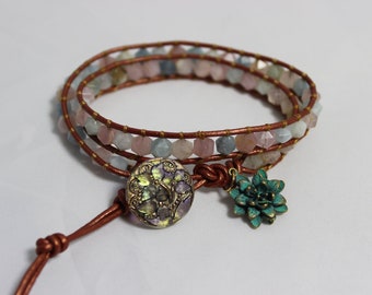 May include: A brown leather wrap bracelet with aqua, pink, and gray gemstone beads. The bracelet has a gold-toned button closure and a turquoise flower charm.