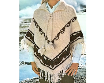 May include: A cream-colored knit poncho featuring a dark brown geometric pattern across the chest and hem. The garment includes a collared neckline, a lace-up front with two hanging tassels, and long fringe detailing along the bottom edge.