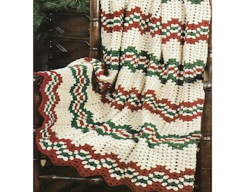 May include: A crocheted blanket with a white background and red and green stripes. The blanket is draped over a wooden chair.