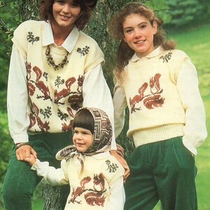 May include: Three people wearing matching cream-colored knit vests with brown squirrel and floral designs. They are also wearing white collared shirts and green pants. One person is wearing a brown hat and another is wearing a patterned scarf.