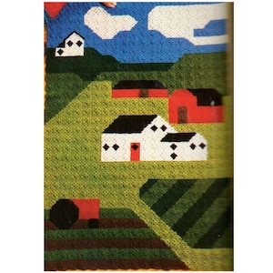 May include: A crocheted wall hanging depicting a countryside scene with houses, fields, and a tractor. The houses are white with black roofs and red doors. The fields are green and brown. The tractor is red and black.