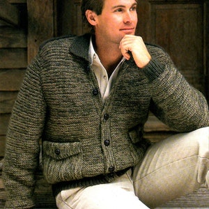 May include: A knitted cardigan in shades of olive green and brown, with a collar, button closure, and two front pockets. The sweater is worn over a white collared shirt and paired with beige trousers. The style is casual and comfortable.