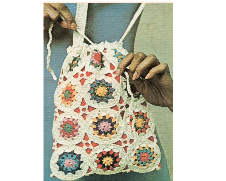 Pu&ograve; includere: Una borsa a cordoncino all'uncinetto con un motivo geometrico colorato. La borsa &egrave; realizzata con filato bianco con accenti rossi, arancioni, gialli, verdi, blu e viola.