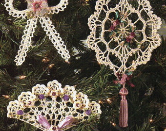 Puede incluir: Tres adornos navideños hechos a mano con ganchillo. Los adornos incluyen un lazo, un diseño en forma de diamante y una forma de abanico. Cada adorno es de color crema con detalles decorativos en rosa, morado y una borla.