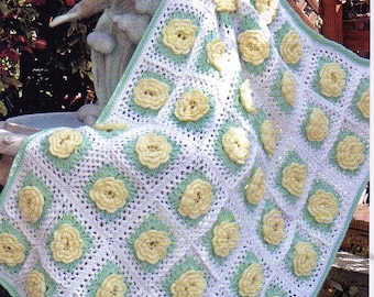 May include: A handmade crochet blanket featuring a repeating pattern of yellow flower appliqués on a white and light green background. The blanket is draped over a stone dolphin statue, showcasing its texture and design.