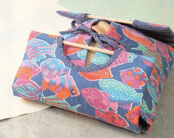 May include: A blue fabric storage bag with a colorful fish print. The bag is folded and has a wooden dowel inside.