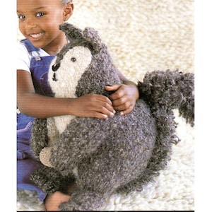 May include: A knitted squirrel toy with a textured grey body and a fluffy tail. The squirrel has a cream-coloured face and a small, black nose. The toy is soft and cuddly, ideal for children.