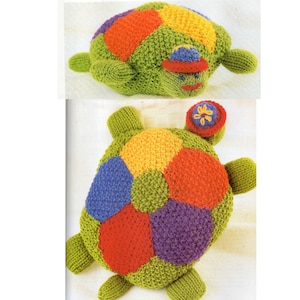 May include: A green knitted turtle with a colorful shell. The shell is made up of six different colored patches: yellow, orange, red, purple, blue, and green. The turtle has a small, knitted flower on its head.