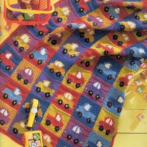 Könnte beinhalten: Eine bunte gestrickte Babydecke mit einem Muster aus Autos in Rot-, Gelb-, Blau- und Lilatönen. Die Decke ist aus verschiedenen Farben Garn gefertigt und perfekt für einen Jungen oder ein Mädchen.