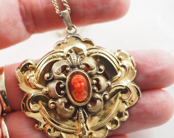 Peut inclure: Un collier avec un pendentif en or orné d'un camée représentant un visage de femme sculpté dans du corail.