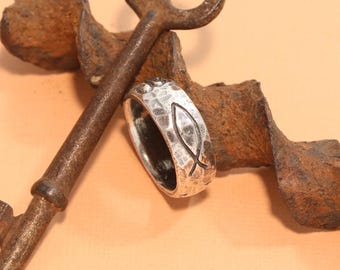 May include: A silver ring with a hammered finish and a raised fish symbol. The ring is resting on a rusty metal key.