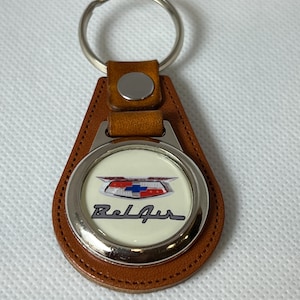 May include: Brown leather keychain with a silver metal ring and a round, white enamel charm featuring a vintage Chevrolet Bel Air logo and the text "Bel Air".