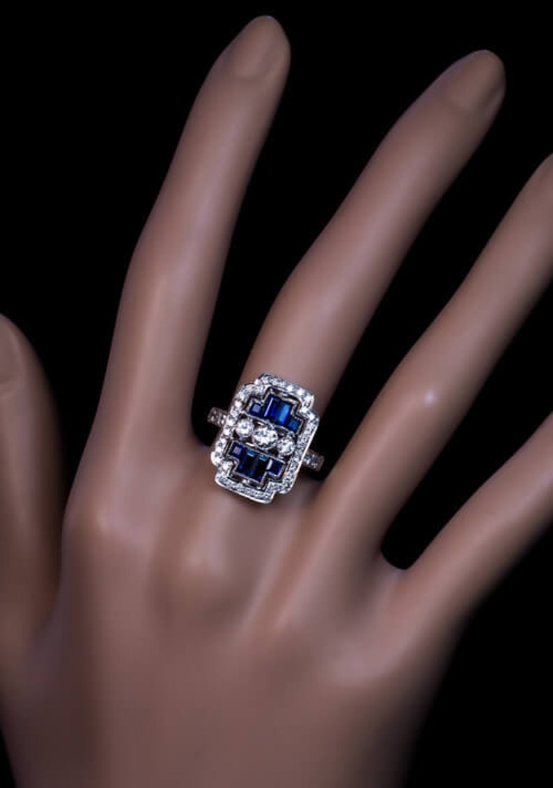 May include: A silver ring with a rectangular design featuring a cluster of blue sapphires and diamonds.