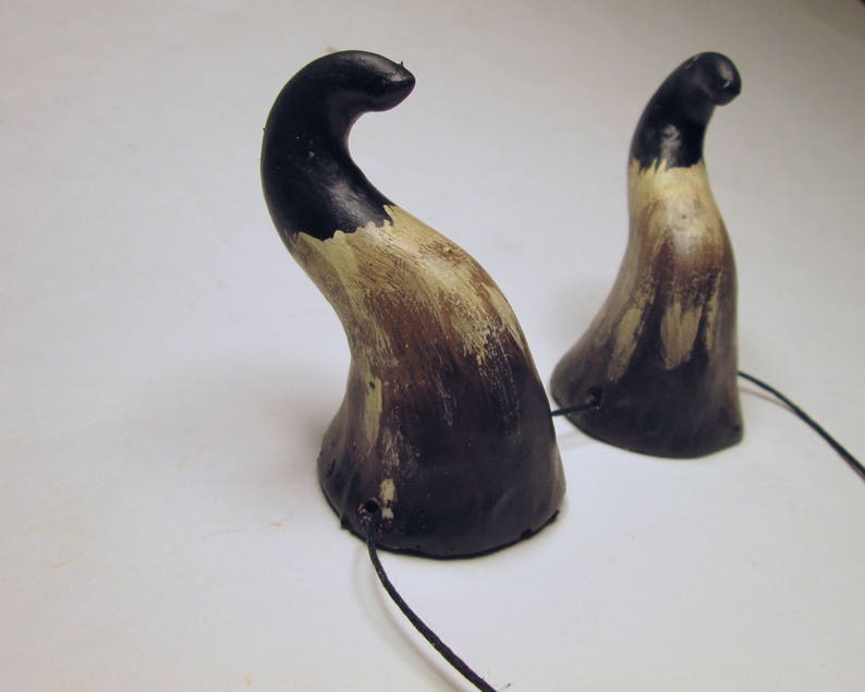 May include: A pair of black and brown horns with a black cord attached. The horns are made of a textured material and have a slightly curved shape.