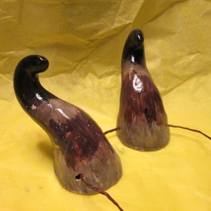 May include: Two brown and black ceramic horns with a wire attached to each. The horns are painted with a mottled brown and black design.