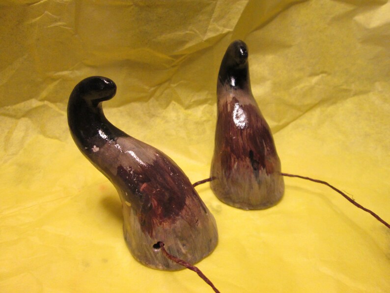 May include: Two brown and black ceramic horns with a wire attached to each. The horns are painted with a mottled brown and black design.