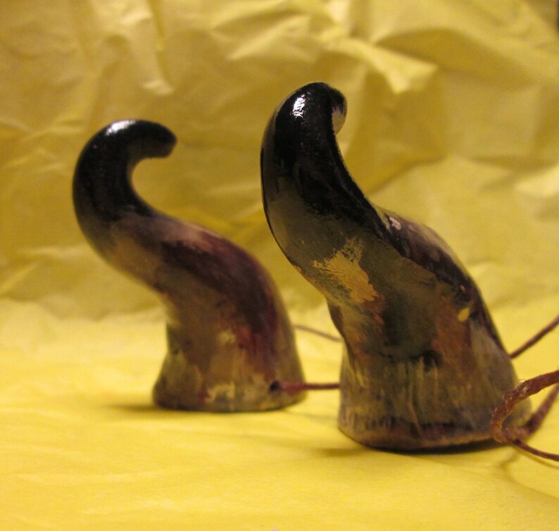 May include: Two black and purple horns with a gold and white paint design. The horns are made of a smooth, hard material and have a slightly curved shape.