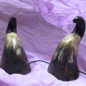 May include: Two black and brown horns with a light brown paint finish. The horns are on a purple background.