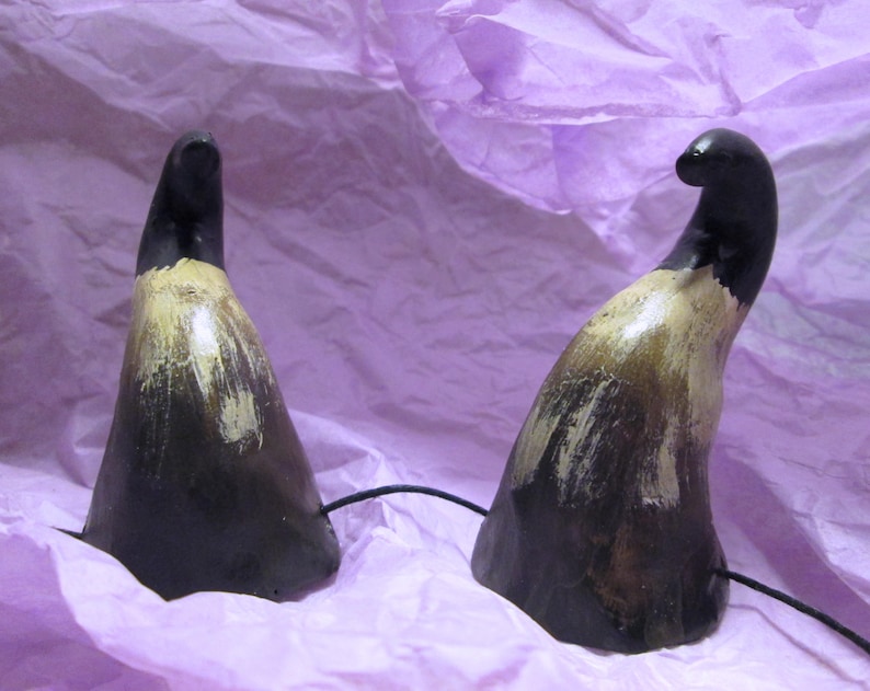 May include: Two black and brown horns with a light brown paint finish. The horns are on a purple background.