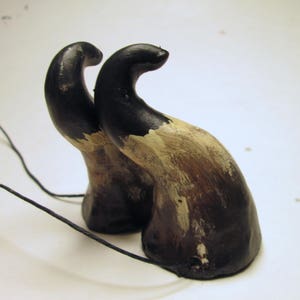 May include: A pair of black and brown horns with a white paint design. The horns are attached to a black cord.