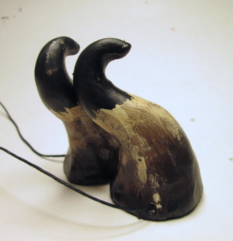 May include: A pair of black and brown horns with a white paint design. The horns are attached to a black cord.