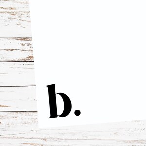 May include: A white background with the black letter "b" and a period. The letter is in a bold, serif font. The image is on a white wooden surface.